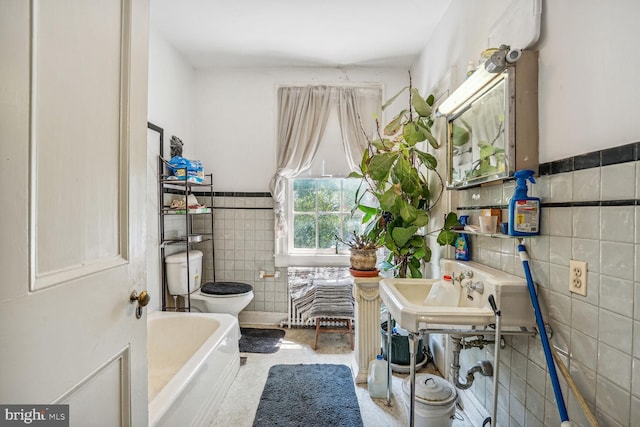 bathroom featuring a tub, tile walls, and toilet