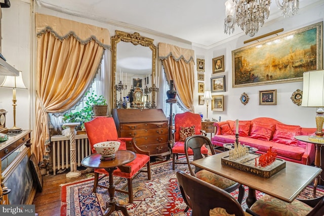 living area with crown molding, radiator, hardwood / wood-style floors, and an inviting chandelier