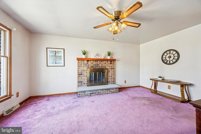 unfurnished living room featuring ceiling fan, carpet, plenty of natural light, and a fireplace