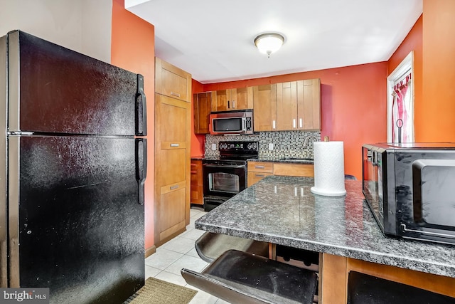 kitchen with tasteful backsplash, sink, a breakfast bar area, light tile patterned floors, and black appliances