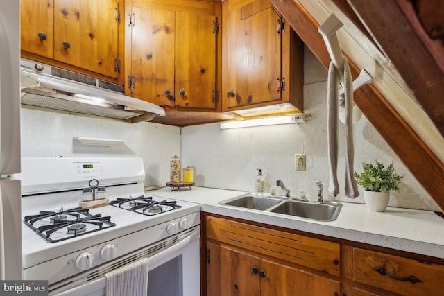 kitchen with under cabinet range hood, white gas range oven, light countertops, and a sink