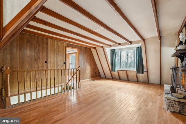 unfurnished living room featuring wood walls, wood-type flooring, and beam ceiling