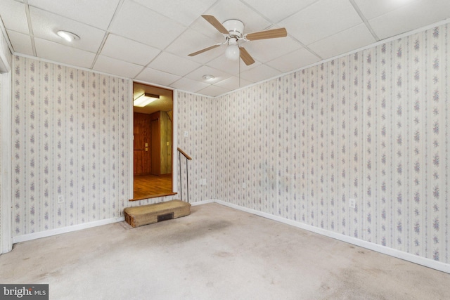 carpeted spare room with wallpapered walls, baseboards, and a drop ceiling