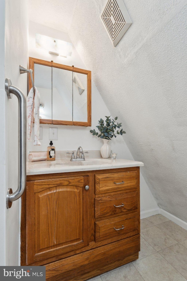 bathroom featuring lofted ceiling, visible vents, vanity, a textured ceiling, and tile patterned flooring