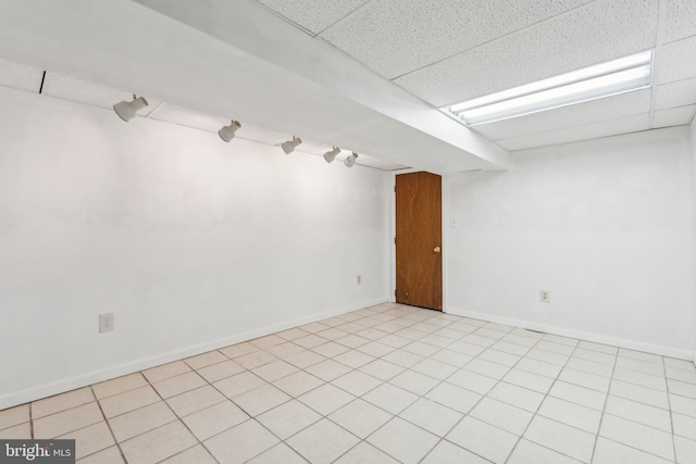 spare room featuring a paneled ceiling and baseboards