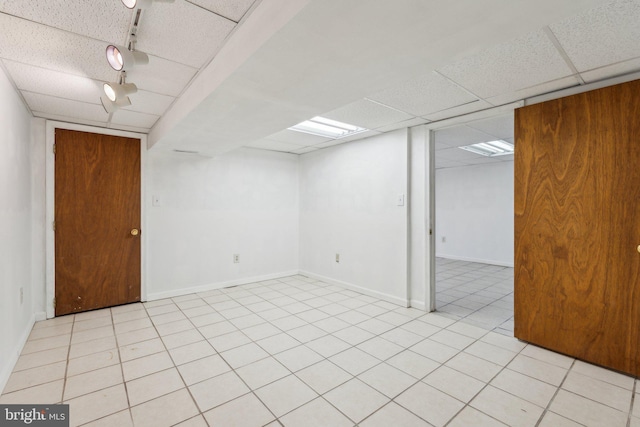 finished basement featuring a drop ceiling, baseboards, and light tile patterned floors