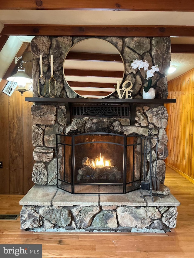 room details featuring wooden walls, wood finished floors, and a stone fireplace