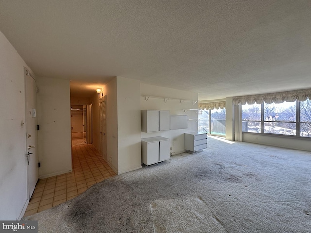 unfurnished living room with light colored carpet and a textured ceiling