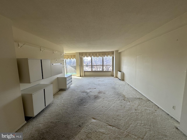 carpeted empty room featuring track lighting and a textured ceiling