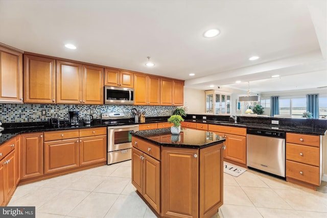 kitchen featuring light tile patterned flooring, stainless steel appliances, a center island, and dark stone counters