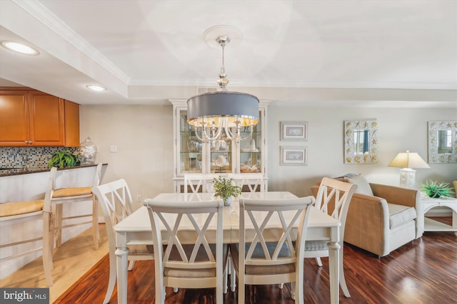 dining area with an inviting chandelier, ornamental molding, and dark hardwood / wood-style floors