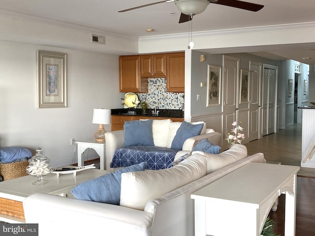 living room with dark wood-type flooring, ornamental molding, and ceiling fan