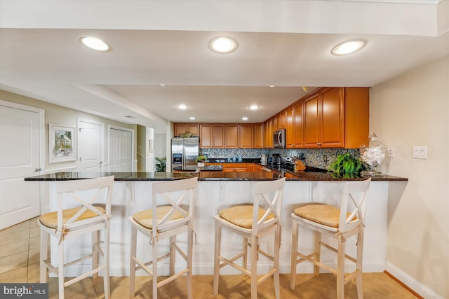 kitchen with stainless steel appliances, tasteful backsplash, a kitchen bar, and kitchen peninsula