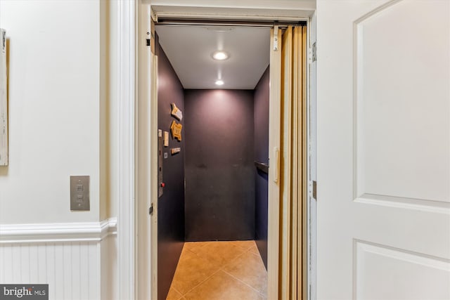 corridor with elevator and tile patterned flooring