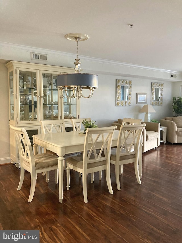 dining room featuring dark wood-type flooring, ornamental molding, and a chandelier