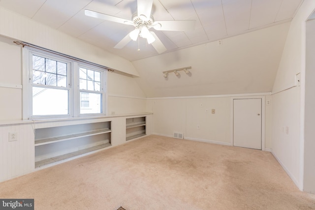 additional living space featuring lofted ceiling, light carpet, ceiling fan, and built in shelves