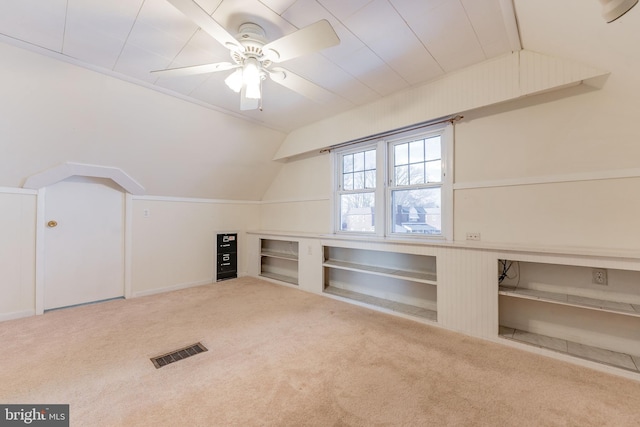 additional living space featuring vaulted ceiling, carpet, ceiling fan, and built in shelves