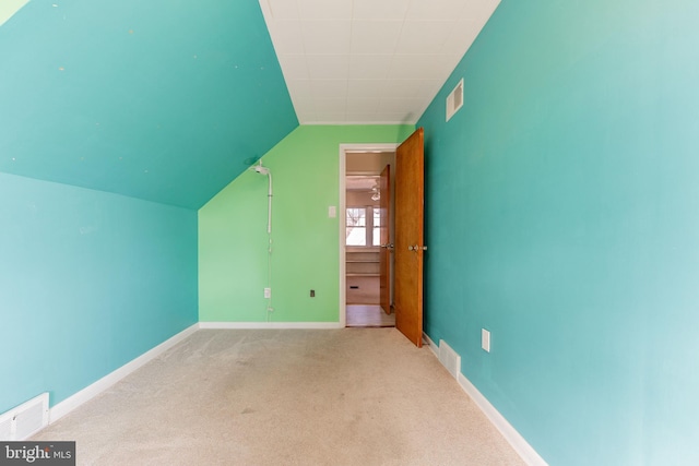 additional living space with light colored carpet and vaulted ceiling