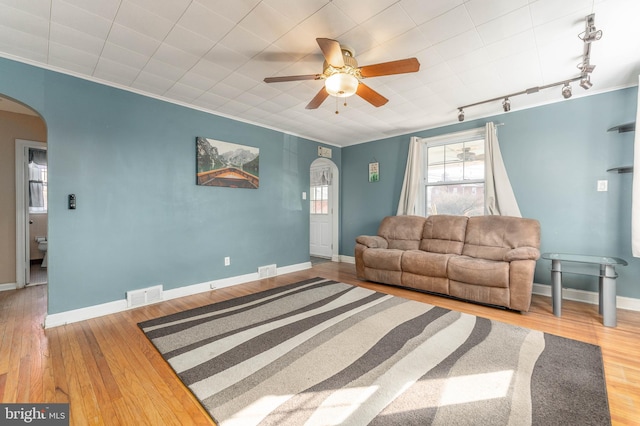 living room with wood-type flooring, ornamental molding, track lighting, and ceiling fan