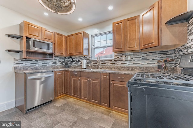 kitchen featuring stainless steel appliances, sink, wall chimney range hood, and decorative backsplash