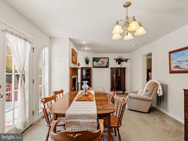 carpeted dining room featuring an inviting chandelier