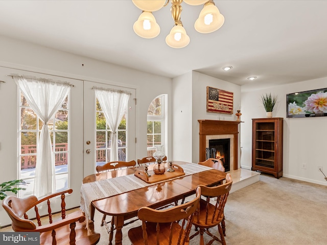 carpeted dining room with a premium fireplace and french doors