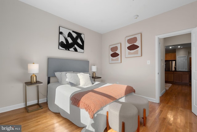 bedroom with light hardwood / wood-style flooring and stainless steel refrigerator