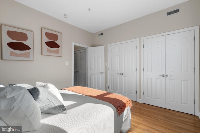 bedroom featuring two closets and light wood-type flooring