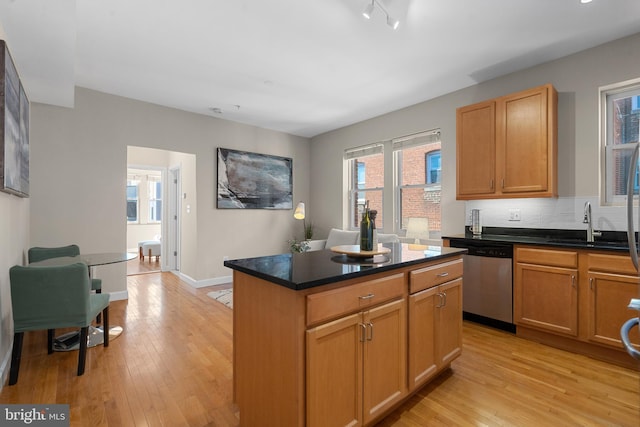 kitchen with tasteful backsplash, light hardwood / wood-style floors, dishwasher, and a kitchen island