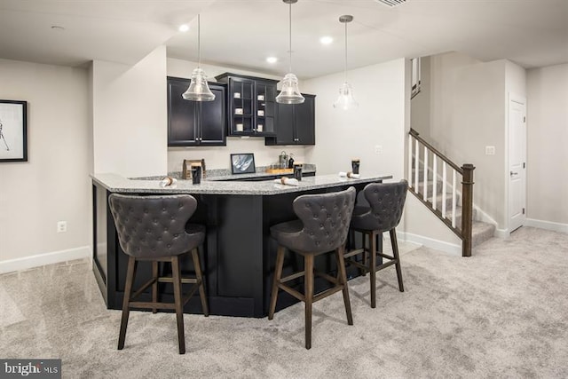 bar featuring light colored carpet, decorative light fixtures, and light stone countertops