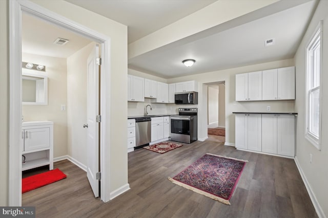 kitchen featuring sink, dark wood-type flooring, stainless steel appliances, and white cabinets