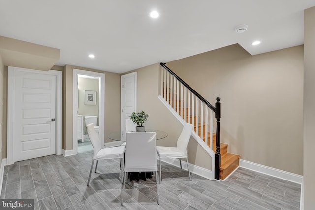 dining room featuring recessed lighting, baseboards, wood tiled floor, and stairway