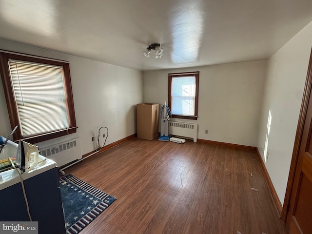 unfurnished bedroom with dark wood-style floors, baseboards, and radiator heating unit