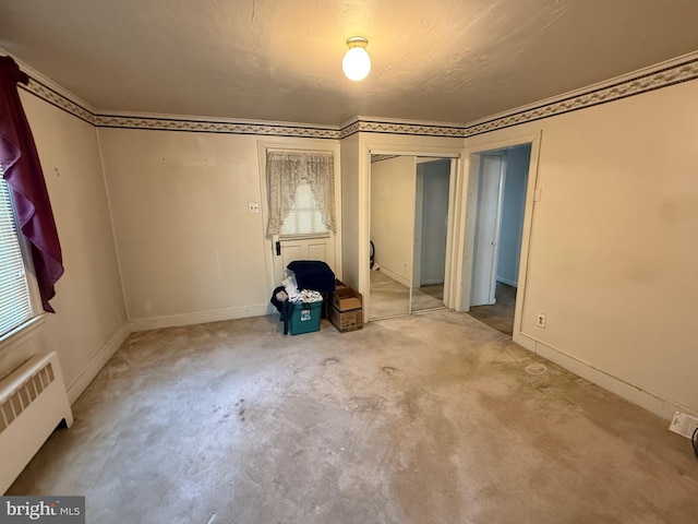 empty room featuring radiator, light colored carpet, and baseboards