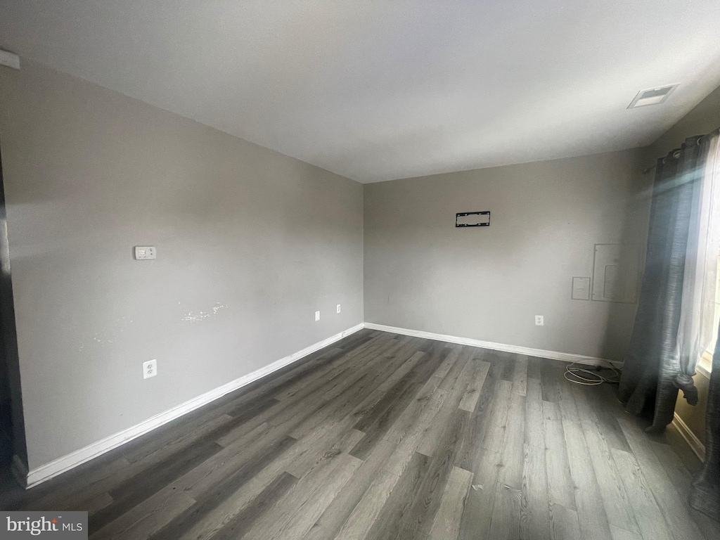 unfurnished room with dark wood-style floors, visible vents, and baseboards