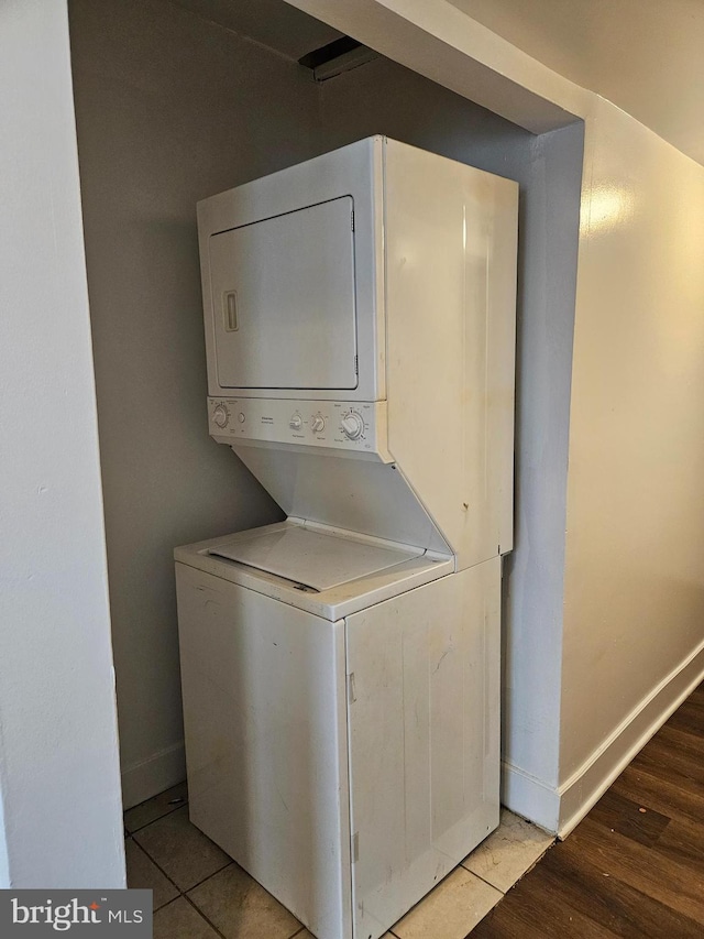 laundry area featuring stacked washer and dryer and light tile patterned floors