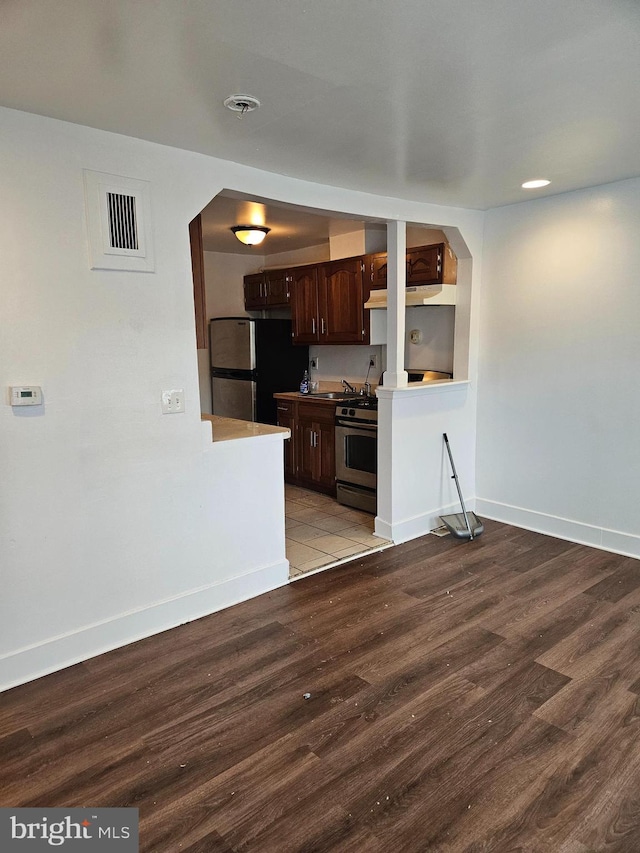 kitchen featuring dark brown cabinetry, stainless steel appliances, and hardwood / wood-style floors