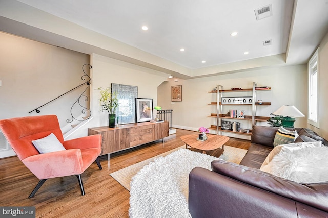 living room with light hardwood / wood-style floors and a tray ceiling