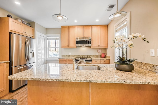 kitchen with stainless steel appliances, hanging light fixtures, sink, and light stone counters