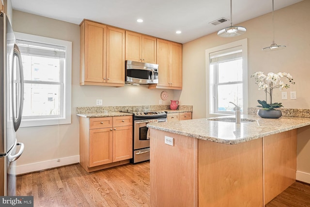 kitchen featuring decorative light fixtures, sink, kitchen peninsula, stainless steel appliances, and light wood-type flooring