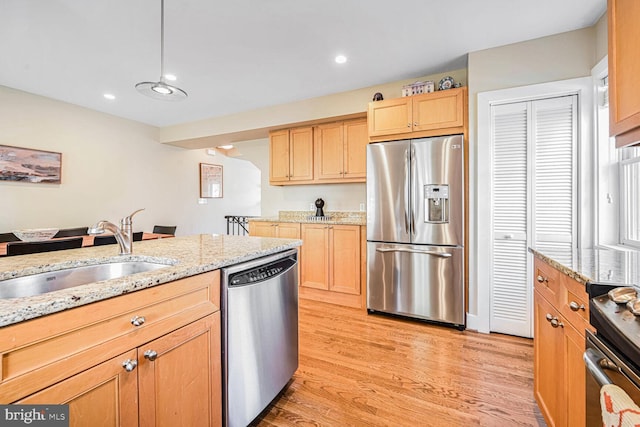 kitchen with sink, light hardwood / wood-style flooring, appliances with stainless steel finishes, light stone countertops, and light brown cabinetry