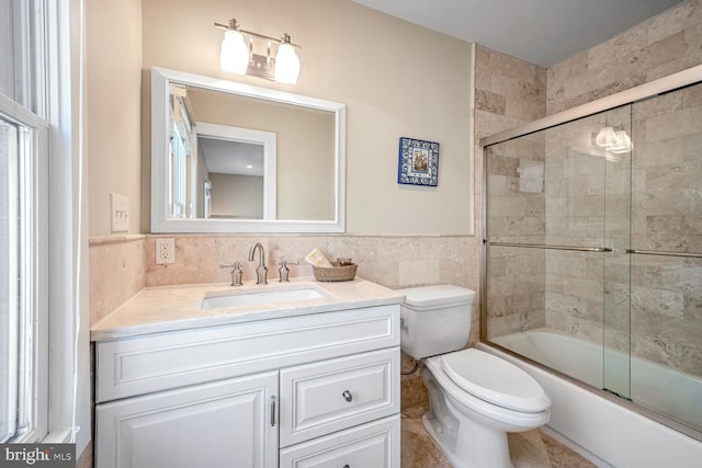 full bathroom with toilet, vanity, shower / bath combination with glass door, and tile walls