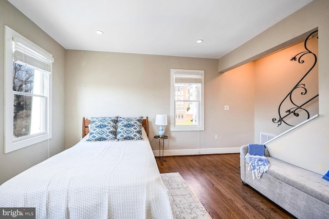 bedroom with multiple windows and dark hardwood / wood-style floors