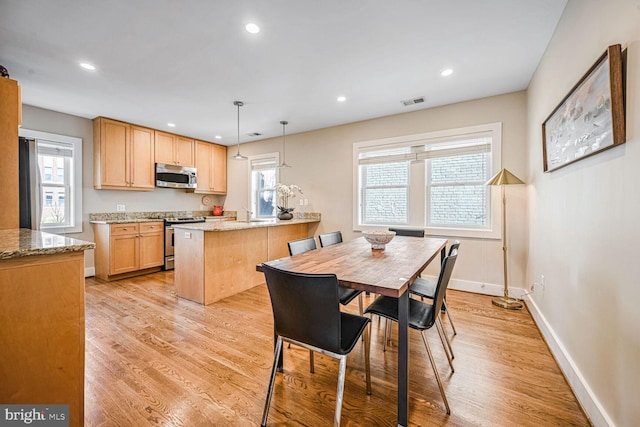 dining area with a wealth of natural light and light wood-type flooring