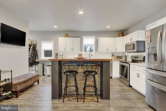 480 Natural Dam Rd, Gettysburg, PA 17325 - kitchen with stainless steel appliances, butcher block counters, a breakfast bar, white cabinets, and backsplash