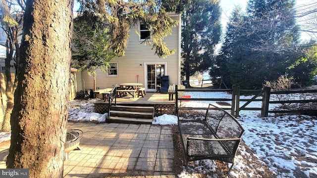 snow covered property featuring a wooden deck and a patio