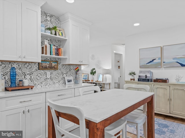 kitchen featuring light stone countertops, white cabinets, a kitchen breakfast bar, and decorative backsplash