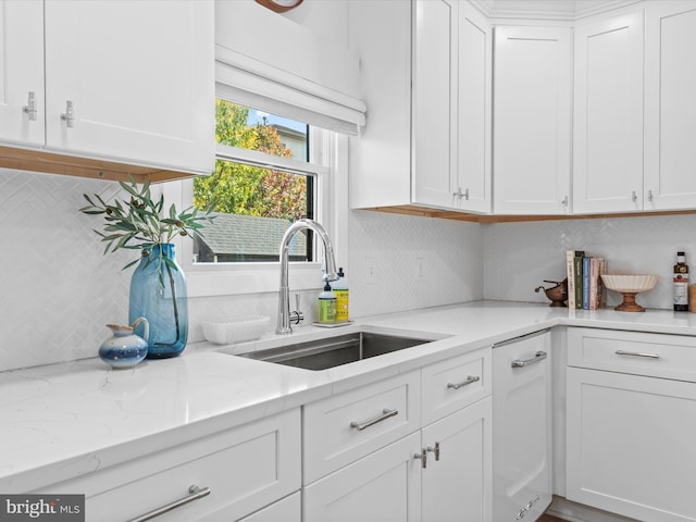 kitchen featuring tasteful backsplash, sink, white cabinets, and light stone counters