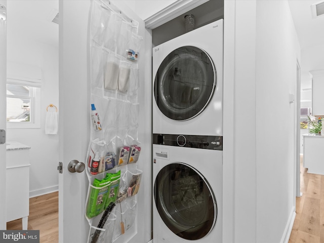 clothes washing area with stacked washer / drying machine and light hardwood / wood-style flooring