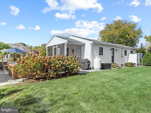 back of house featuring a lawn, a sunroom, and a patio